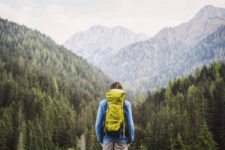 Young backpacking man traveler enjoying nature in Alps mountains